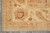 Corner detail of ivory main border with rust palmette, leaf scrolls and hand-tied fringe