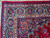 Close-up of ivory and navy border corner with rosettes, palmettes and white cotton fringe