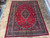 Top down showroom photograph of red and navy hand-knotted wool Persian rug in 9x12 size