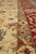Border close-up highlighting camel guard stripe against crimson ground with pale green leaf scrolls