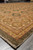 Side perspective of the wool rug corner where gold border medallions meet dark olive band