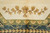 Golden leaf and lotus spray woven into the plain beige field above green border