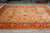 Angled floor view of the beige and red Oriental rug with all-over floral vinework and guard stripes