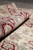 Rolled 6'1" x 9'2" rug showing pile depth, sheen and burgundy floral border