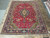 9'7" x 12'10" Persian Tabriz rug laid flat on tile floor showing red field and navy border