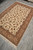 6x9 wool and silk area rug seen from the corner, ivory ground and tan border