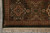 Corner detail with ivory floral medallion, olive border and hand-tied cotton fringe on grey tile