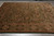 Dark green wool field with olive and rust palmettes photographed at an angle on grey tile floor