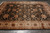 Hand-knotted wool rug photographed on grey tile, black field framed by a wide ivory floral border