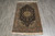 Small 4x5 Persian rug photographed flat on grey tile showing ivory fringe at both ends