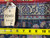 Original inventory tag reading 5.6 x 10 beside a tape measure on the blue rug back