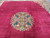 Overhead detail showing the round floral medallion centered on a plain magenta red wool field