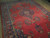Angled view of coral red field, indigo medallion and teal floral border on wool pile