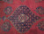 Close-up of indigo medallion filled with coral rose heads and pale ivory center cartouche