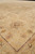 Angled close-up of a beige border rosette with rust, sage and charcoal outlining in wool