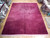 12x15 Chinese rug laid on parquet showroom floor beside stacked rolled oriental rugs