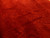 Detailed macro of hand-carved bamboo leaf motifs across the lustrous red wool pile