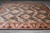 Hand-knotted wool rug seen lengthwise, wide burgundy border framing the dark black damask field