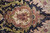 Close-up of ivory cartouche with rose sprays, olive leaves and beaded gold edging on black