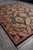 Large 9x12 area rug angled across a showroom floor, black field and burgundy frame