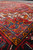 Low angle across dense wool pile showing blue spandrel, saffron accents and checkered guard