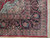 Corner detail showing multi-band navy border, rose palmettes, ivory guard stripes and clean cotton fringe
