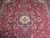 Close-up of ivory and navy center medallion surrounded by scrolling vines on berry red field