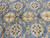 Detail of large cream and gold rosettes floating on a denim blue hand-knotted wool field