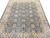Angled view of the ivory main border framing the slate blue field of rosettes and vines