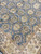 Close view of blue-gray field with olive, brown and ivory rosettes beside the ivory border