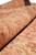 Close macro of rolled pile showing coral, pink and gold floral drawing in soft wool