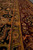 Border detail with olive gold guard stripe separating black field from burgundy floral outer band