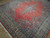 Angled view of the 9x11 wool rug, salmon red field with blue floral sprays