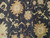 Close-up of oversized palmettes and curling leaves in gold and sage on black wool pile