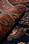Rolled edge showing pile depth, red border medallions and the deep indigo field beside it