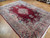 9x12 Kerman wool rug viewed at an angle, deep burgundy field framed by navy floral border