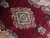 Close-up of the ivory and rose center medallion with open roses on burgundy wool pile