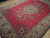 8x11 red Persian area rug at an angle showing sage and rose floral sprays