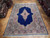 Royal blue Kerman rug laid on parquet showroom floor, ivory medallion and rose floral borders