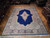 Angled view of hand-knotted wool Kerman rug showing garden border, corner spandrels and blue field