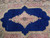 Close-up of ivory and rose central medallion with scrolling vines on deep royal blue ground
