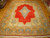 10 x 14 Kerman Persian rug laid on parquet floor showing full red field and saffron border