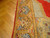Angled border detail showing navy panels, saffron gold vines and red rosettes beside oak parquet flooring