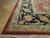 9x12 Indian Agra rug corner on hardwood floor showing ivory fringe and red selvage