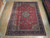 9'1" x 12'3" Persian Qazvin rug displayed flat on a light wood showroom floor