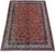Angled full view of coral Sarouk rug showing all-over bouquet repeat and cream ivory borders