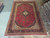 9'6" x 14' hand-knotted Kashan rug laid on showroom floor beside rolled Oriental rugs