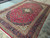 Angled view showing ivory corner spandrels, indigo main border and crimson floral field detail