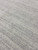 Macro texture shot revealing hand-knotted wool fibers in mottled gray and cream across the field