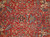 Black eight-armed starburst medallion among angular leaf forms across the rustic red Heriz field